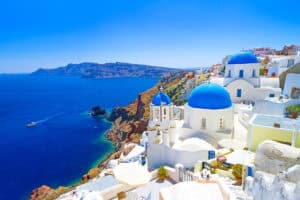 White churches with blue domes on a cliff overlooking the sea on Santorini Island.